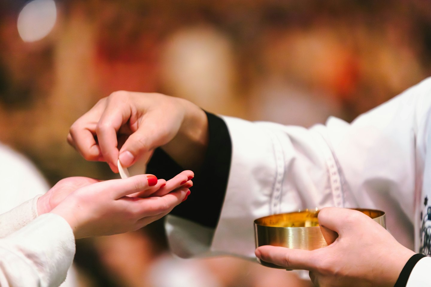 A person in a white robe gives a communion wafer.
