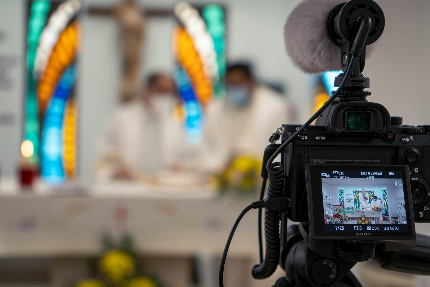 A camera on a tripod records a church service.